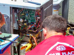 A technician from Our Place Air & Home Repair repairing the internal wiring of an HVAC unit in Orlando, FL.