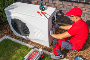 A technician in a red shirt and cap repairing an outdoor air conditioning unit for Advanced Mechanical Contractors, Inc. in Nashville, TN.