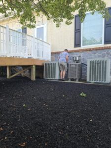 A Fletchers Plumbing and Heating technician servicing outdoor air conditioning units in Smyrna, DE