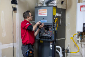 A technician servicing an indoor furnace for Allred Heating Cooling Electric in Auburn, WA.