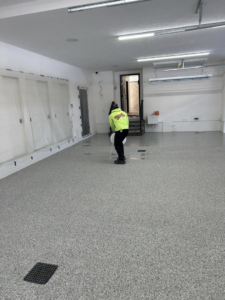A technician from DuraFloor Epoxy Pros performing final work on a newly installed epoxy garage floor in Akron, OH.