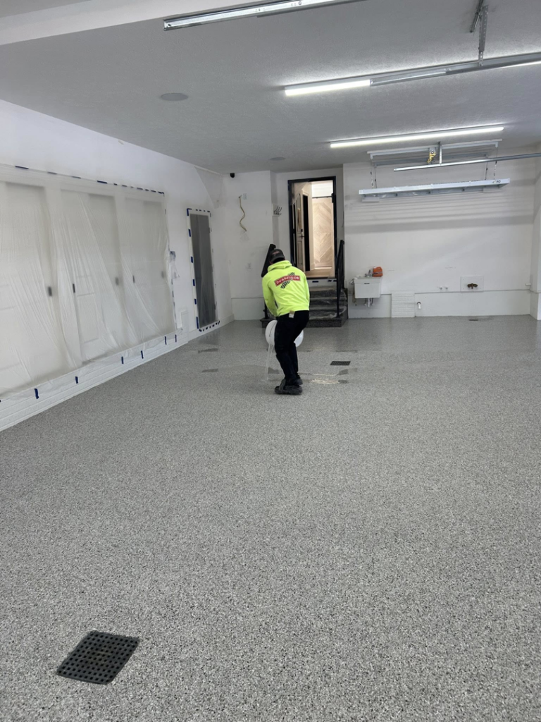 A technician from DuraFloor Epoxy Pros performing final work on a newly installed epoxy garage floor in Akron, OH.