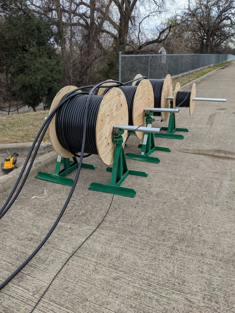 Large spools of black telecom cable on stands, ready for installation by RamTelecomLLC, a general contractor in Houston, TX