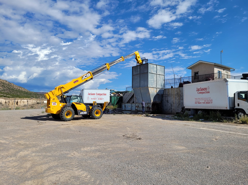 A JCB telehandler loading waste into a compactor at Jackson Compaction in Albuquerque, NM.