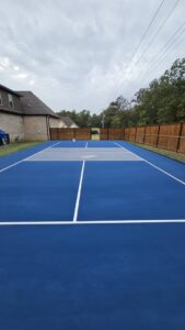A tennis or pickleball court being professionally painted blue with white lines by Acosta Painting LLC in Jonesboro, AR.