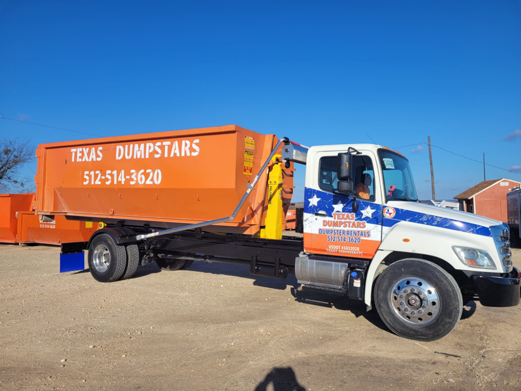 A Texas Dumpstars truck with an orange roll-off dumpster ready for delivery in Hutto, TX.