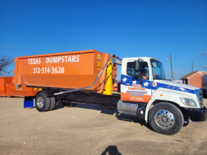 A Texas Dumpstars truck with an orange roll-off dumpster ready for delivery in Hutto, TX.