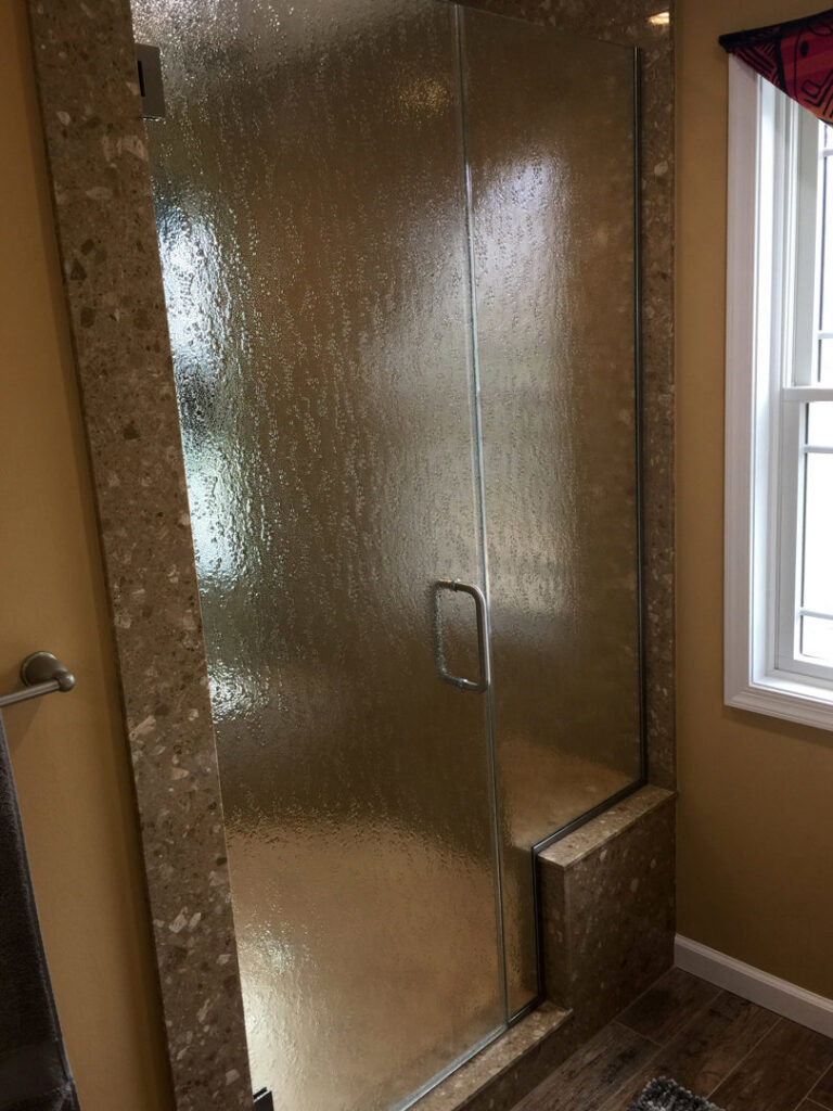A stylish shower featuring textured glass and natural stone-look tiling, installed by Lehigh Shower Glass in Bethlehem, PA