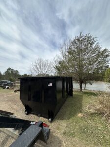 Three dumpsters from American Dumpster Rentals in black, tan, and red colors, placed in a snowy setting in Morrilton, AR.