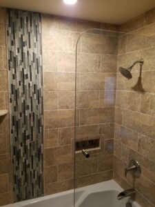 Tiled bathroom shower and tub installation with a mosaic accent by APS Residential Services in Livonia, MI.
