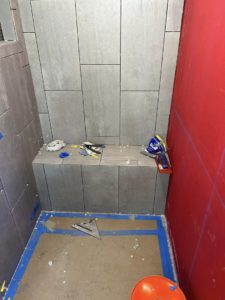 A newly tiled shower bench and walls with grey tiles, showing ongoing work by G-P Construction in Springfield, OR.