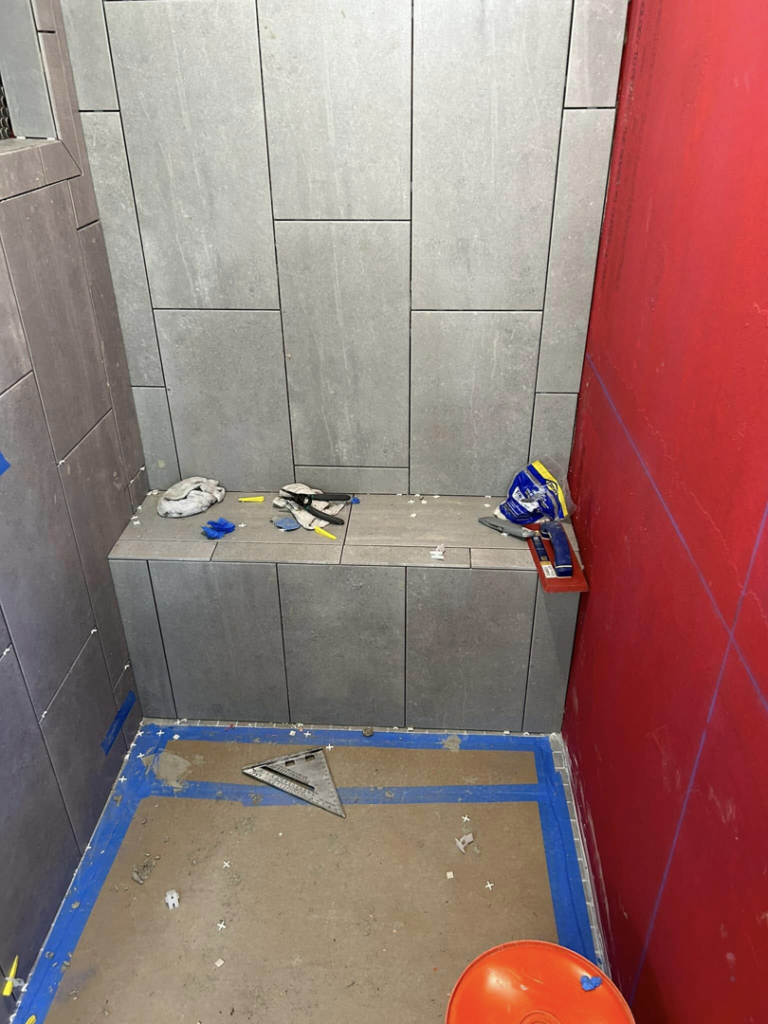 A newly tiled shower bench and walls with grey tiles, showing ongoing work by G-P Construction in Springfield, OR.