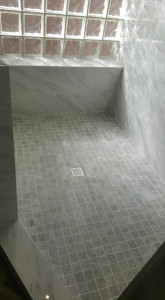 A newly tiled shower floor and walls with decorative glass blocks by Southwest Restoration & Design, Inc. in Peoria, AZ.
