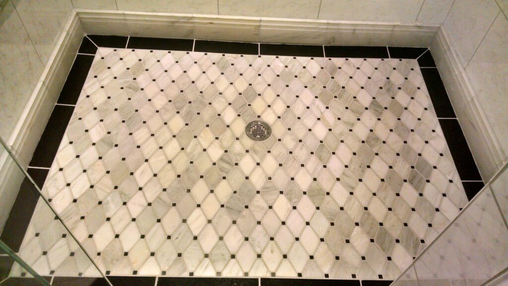 A close-up of a beautifully tiled shower floor with a decorative pattern by Unique Construction Services in Knoxville, TN