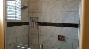 A newly tiled shower with a clear glass door installed by Southwest Restoration & Design, Inc. in Peoria, AZ.