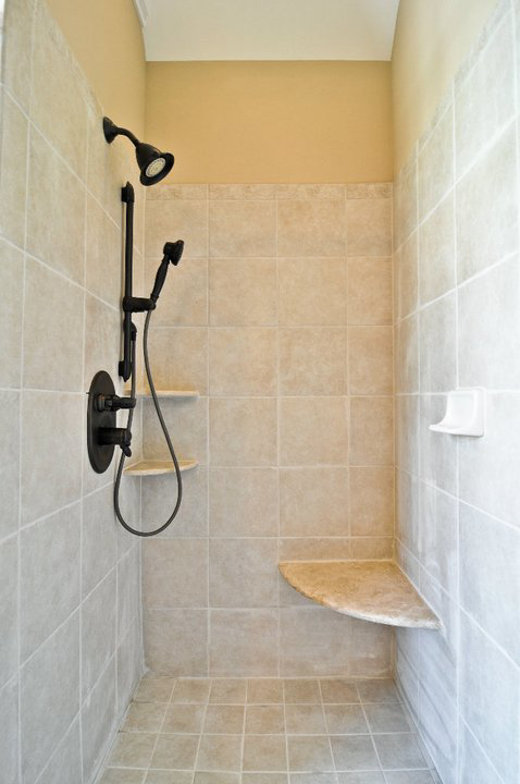 A modern tiled shower with dark bronze fixtures and built-in shelves, expertly installed by Nixon Construction in Nashville, TN.