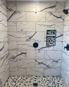 Newly installed tiled shower with a pebble floor as part of a bathroom remodel by Vander Wal Contracting, LLC in Bismarck, ND