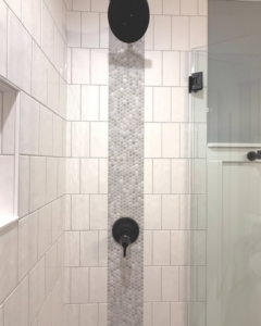 A beautifully tiled shower with a decorative accent strip and modern black fixtures installed by Valley Wide Design & Build in San Tan Valley, AZ.