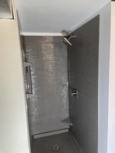 Tiled shower installation with a modern shower head and grab bar by DeJean Home Renovation in Yankton, SD.