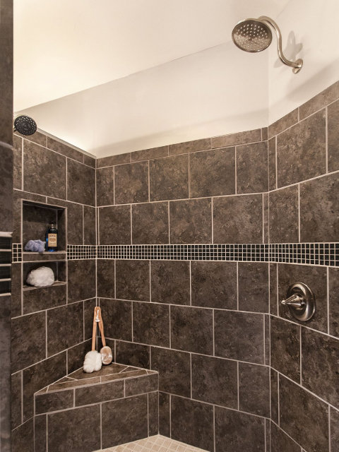 A newly installed tiled shower with a built-in niche and bench by Indy Renovation in Indianapolis, IN.