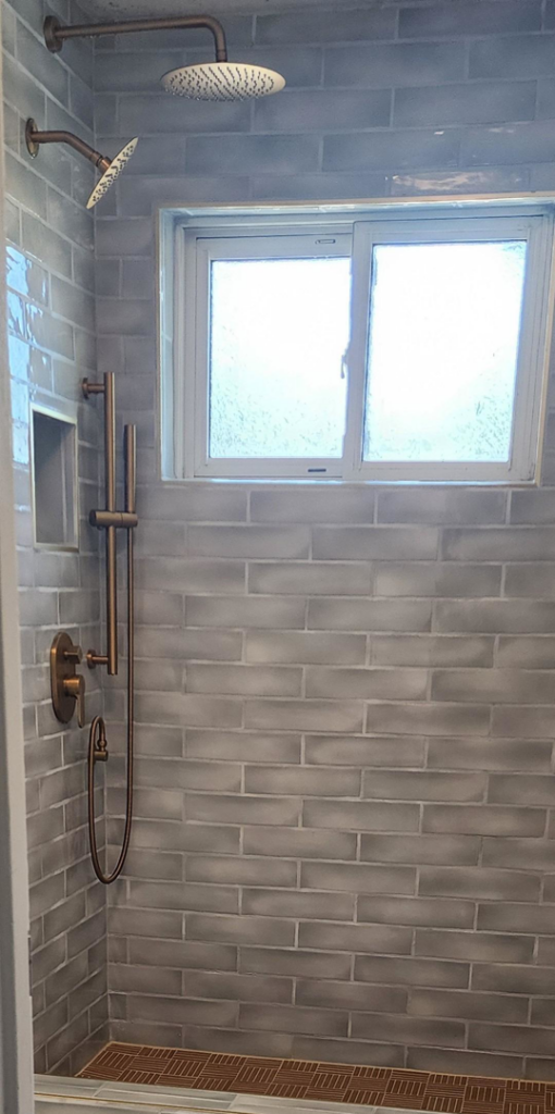 A newly tiled shower with modern bronze fixtures installed by Peak2Peak Connect Handyman Services LLC in Arvada, CO.