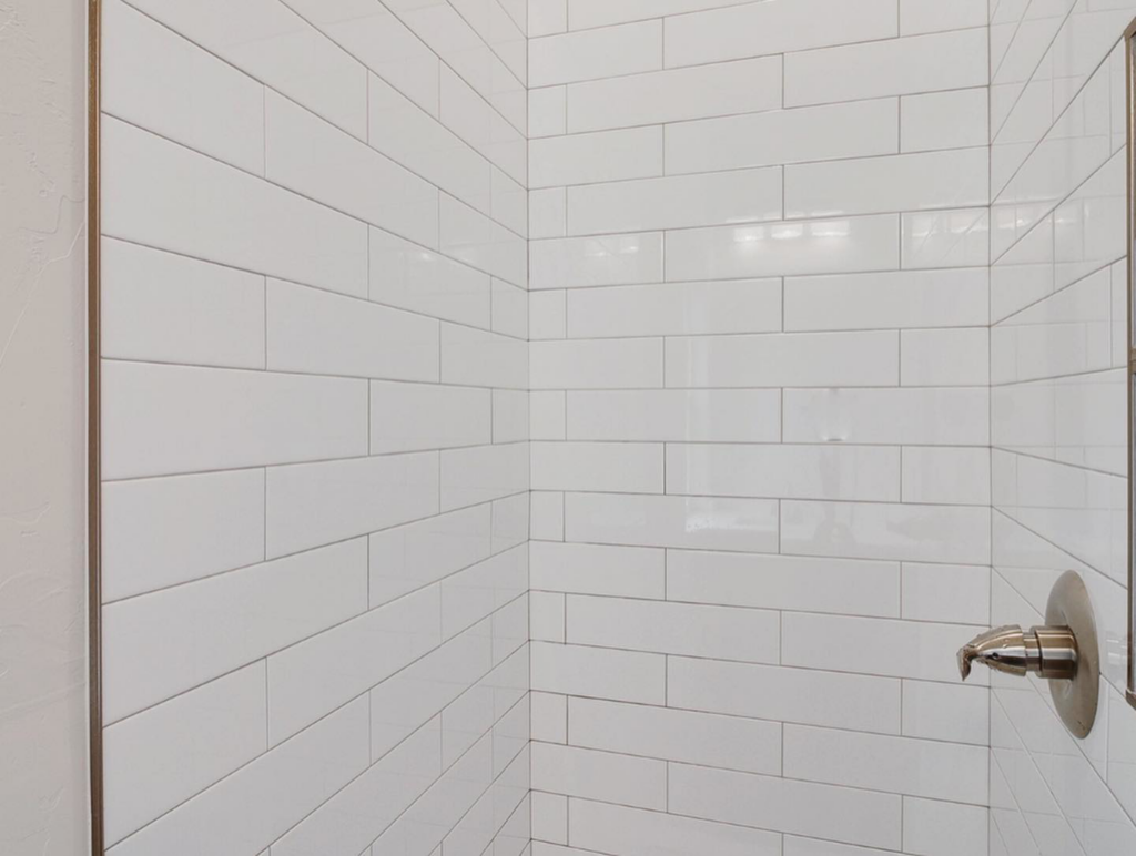 Close-up of a beautifully tiled shower wall with a new shower head by Power Roofing & Construction in Norman, OK.