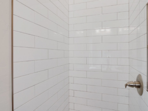 Close-up of a beautifully tiled shower wall with a new shower head by Power Roofing & Construction in Norman, OK.