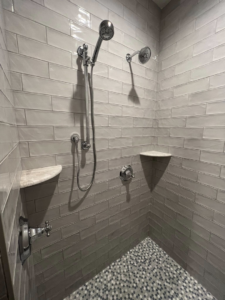 A newly tiled shower with subway wall tiles and a mosaic floor, installed by Tri Lake Construction in Madison, WI
