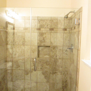 A newly installed tiled shower with a glass door and modern fixtures by Werling Construction in Newport News, VA
