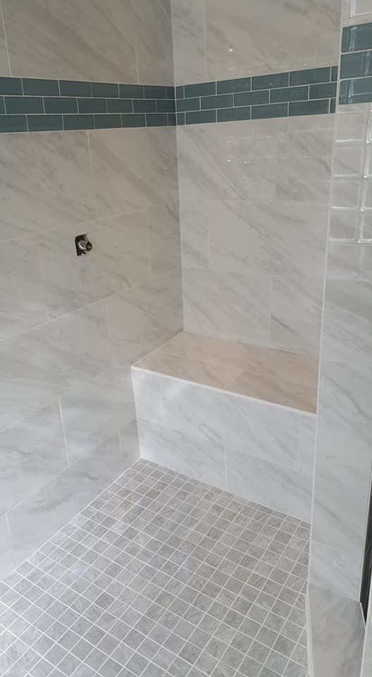 A newly tiled shower interior with a built-in bench by Southwest Restoration & Design, Inc. in Peoria, AZ.