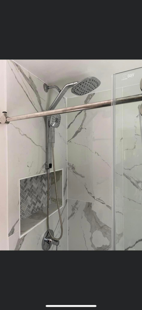 Close-up of a modern tiled shower with a niche, part of a bathroom remodel by Do It All Contracting in Rochester, NY.