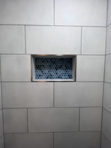 A close-up of a beautifully tiled shower niche with blue hexagonal mosaic tiles, a detail from a project by Great Home Construction LLC in Annapolis, MD.
