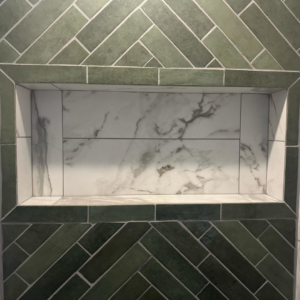 Expertly installed tiled shower niche with green herringbone and white marble-look tiles by City Home Improvement Inc in Portland, OR.