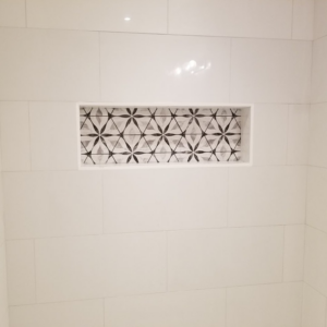 A beautifully tiled shower niche with decorative accent tiles installed by Huynh Design & Remodeling in Alexandria, VA.