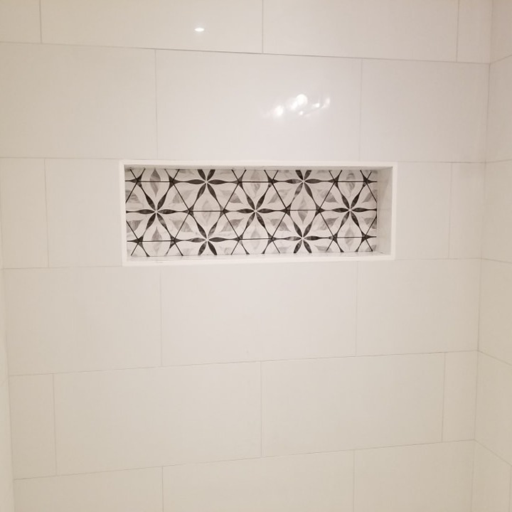 A beautifully tiled shower niche with decorative accent tiles installed by Huynh Design & Remodeling in Alexandria, VA.