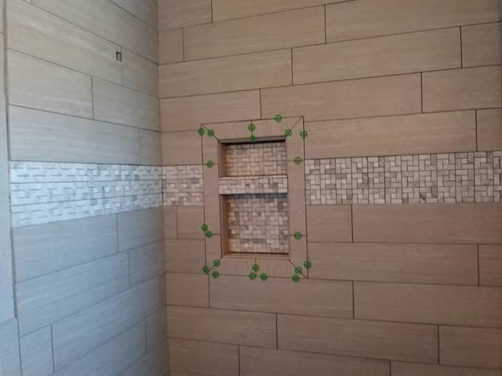 A newly tiled shower wall with a built-in niche and decorative mosaic band by TaylorMade handyman services in Roswell, NM