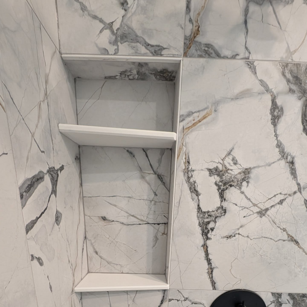 A newly installed tiled shower niche with a white shelf by Ensotile - Atlanta Bathroom Remodeling in Stone Mountain, GA