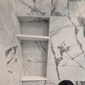 A newly installed tiled shower niche with a white shelf by Ensotile - Atlanta Bathroom Remodeling in Stone Mountain, GA