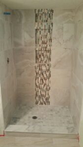 A newly tiled shower stall featuring a decorative vertical mosaic tile strip by ALKA Construction/ Handyman Services in Layton, UT