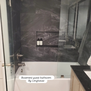 A newly tiled shower wall and bathtub installation in a basement guest bathroom by Longhouse Construction Inc. in Estacada, OR.