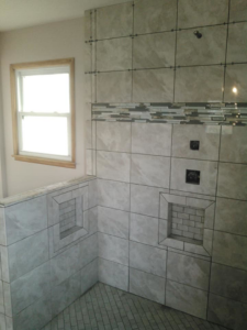 Detailed view of a newly tiled shower wall with decorative band and built-in storage niches by Paulus Contracting in Fayetteville, OH