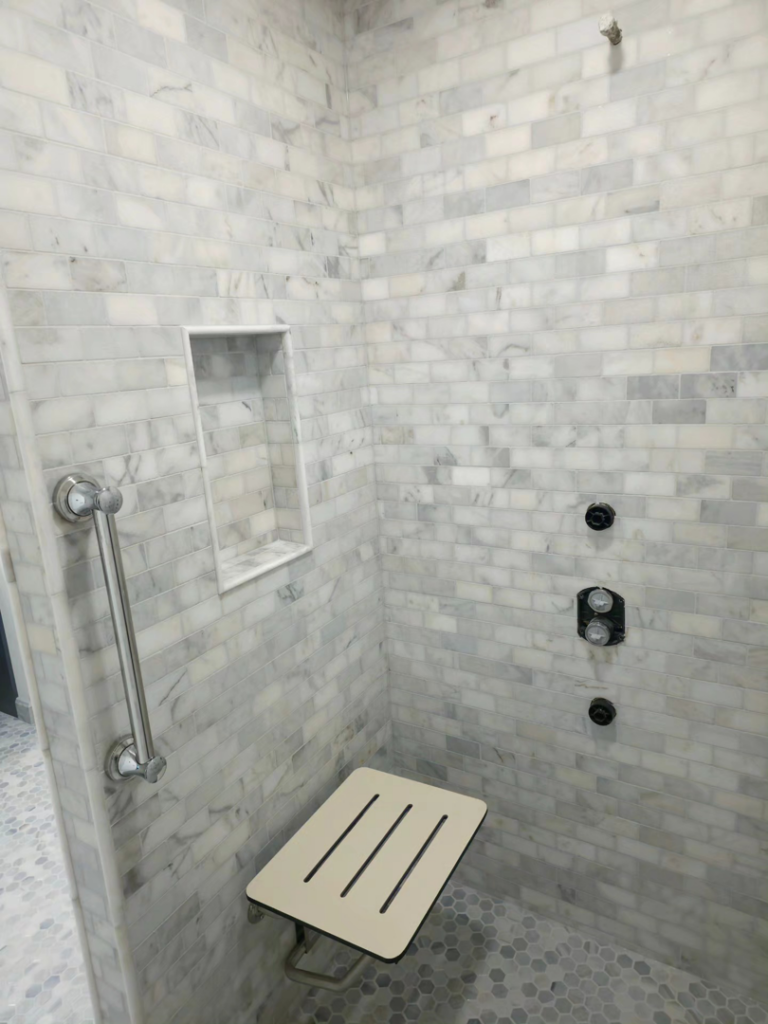A beautifully tiled shower with a grab bar and fold-down seat installed by Tyler the Tiler in Jefferson, WI.