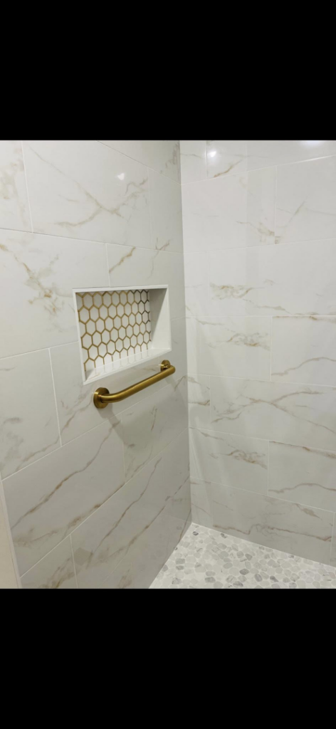 A beautifully tiled shower with a built-in niche and safety grab bar by Craft Tile Co in Springfield, MO.