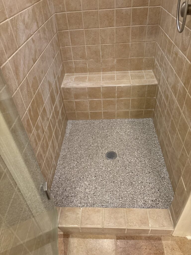 A clean tiled shower with a light flake epoxy floor installed by Donnelly J. LLC Epoxy in St. Charles, MO.