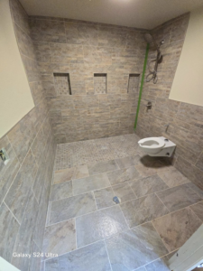 An overhead view of a newly tiled walk-in shower area with built-in niches and a toilet, completed by Torres Services in Anchorage, AK.