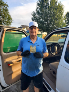 A Tote Away LLC employee in uniform stands by a truck with a green dumpster in the background in Lafayette, LA.