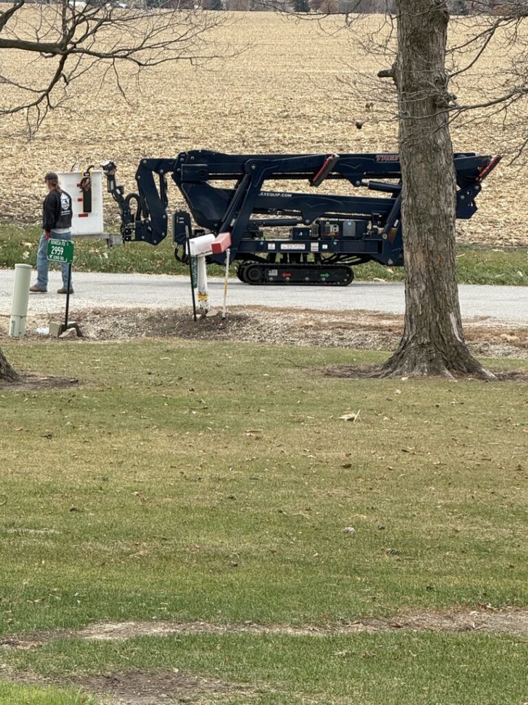 A tracked spider lift, specialized tree service equipment, parked on a roadside by SKV Tree Service in Morris, IL.