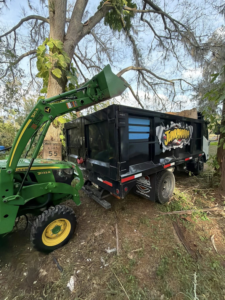 A tractor loading various junk and debris into a Junkamaniafl removal truck during a job in Greenwood, IN.