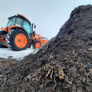 A tractor working on a large organic compost pile at Big Lake Organics in Ashland, WI, for waste processing.