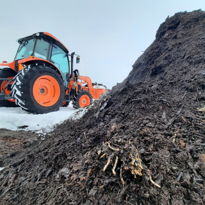 A tractor working on a large organic compost pile at Big Lake Organics in Ashland, WI, for waste processing.